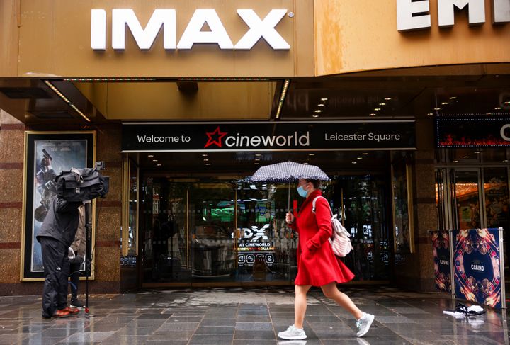 A woman holds an umbrella as she walks past a Cineworld in Leicester's Square.