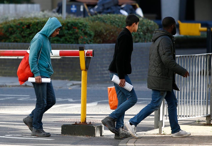 Two unaccompanied minors from the Jungle migrant camp in Calais walk outside an immigration centre after being processed after their arrival in Britain in 2016