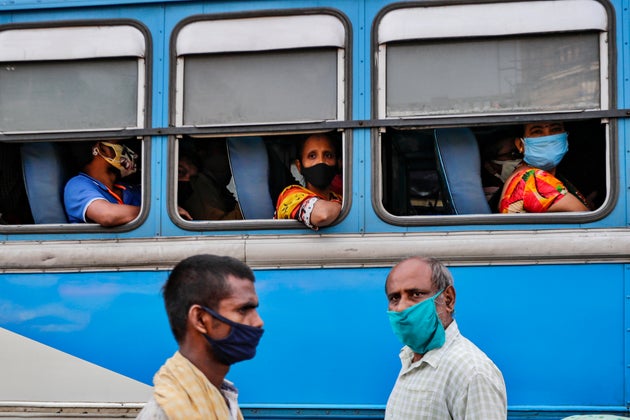 Commuters wearing face masks to prevent coronavirus wait inside a bus as pedestrians walk past at a bus...