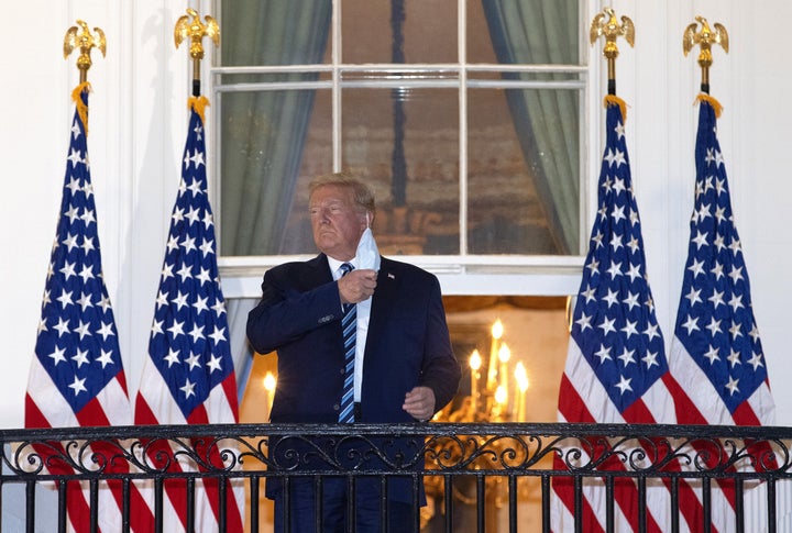 US President Donald Trump removes his mask upon return to the White House from Walter Reed National Military Medical Center on October 05, 2020 in Washington, DC. 