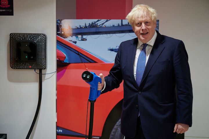 Britain's Prime Minister Boris Johnson holds an electric vehicle charging cable during a visit to the headquarters of Octopus Energy in London.