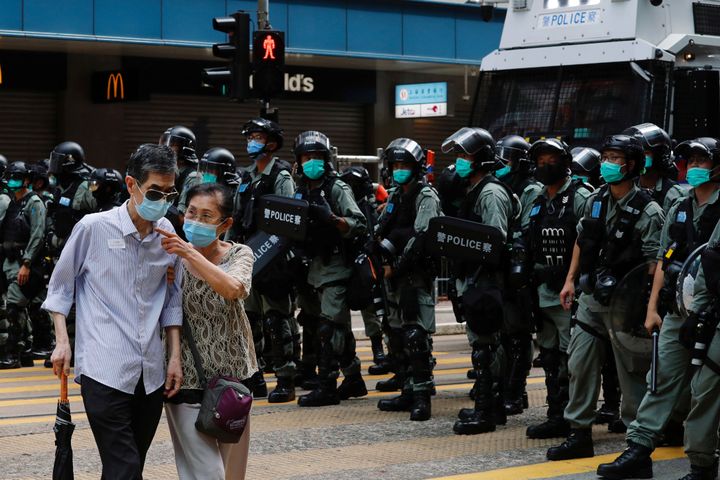 デモの警戒にあたる警察部隊の前を通る通行人＝2020年7月