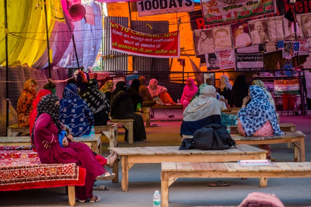 People sit at a distance as they continue their protest against CAA amid a lockdown order by Delhi's...