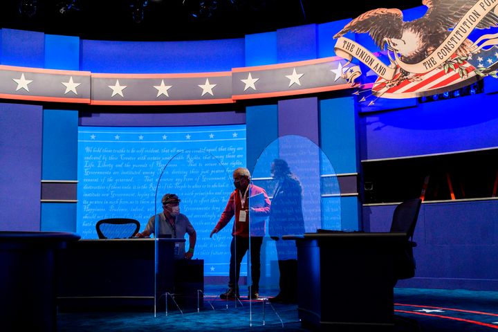 Workers install plexiglass protections at the vice presidential debate hall in Utah. Experts say the barriers are not remotely adequate for preventing COVID-19 transmission.