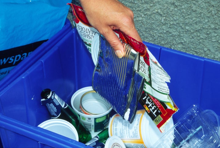 File photo of a person adding items into a recycling blue box.