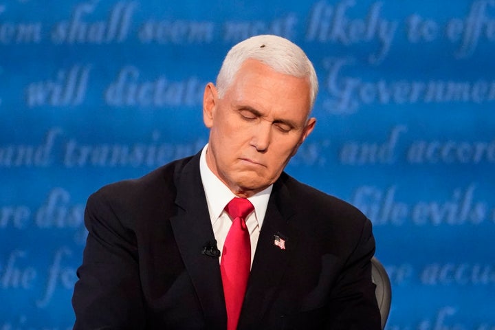 Vice President Mike Pence has a visitor as he listens to Democratic vice presidential candidate Kamala Harris during the vice