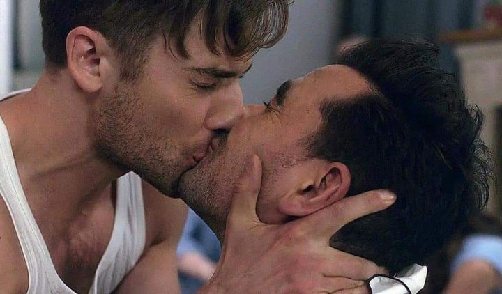 (L-R) Ted (Dustin Milligan) shares a kiss with David Rose (played by Levy).