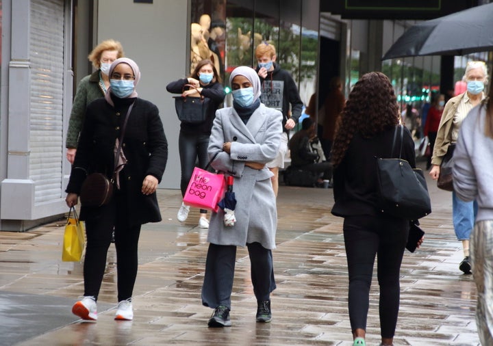 Women walk along London's Oxford Street while while wearing face masks as a preventive measure against the spread of coronavirus