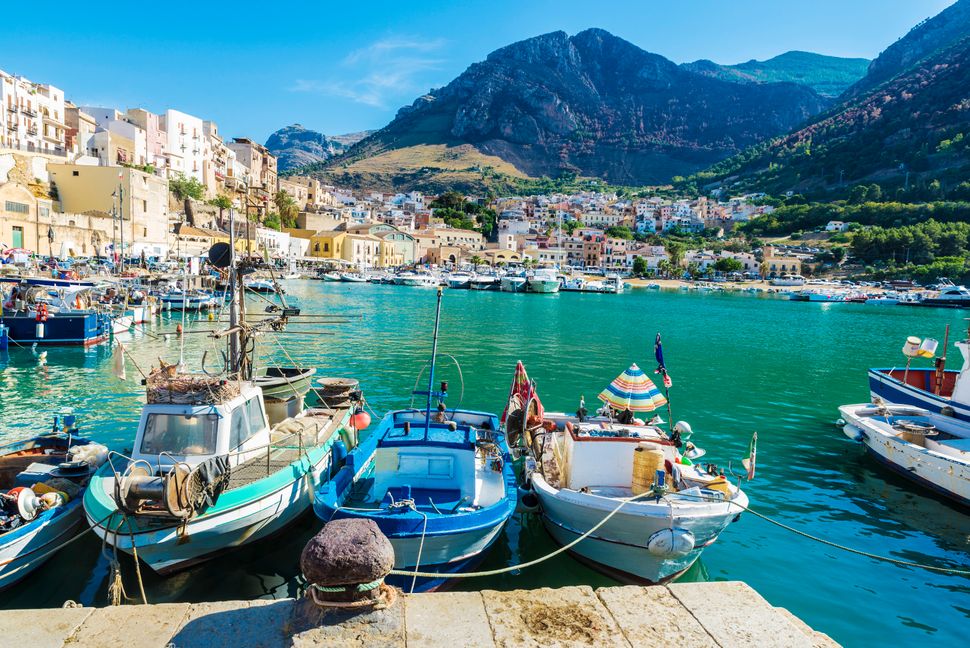 Fishing port with old wooden fishing boats docked at the marina in summer in Castellammare del Golfo in Sicily, Italy