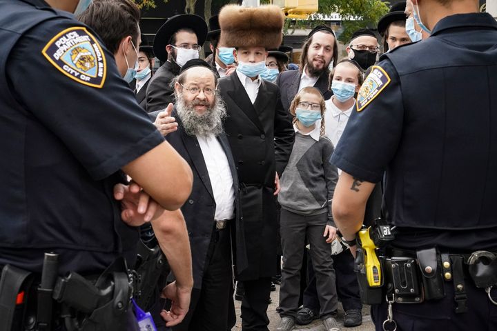 Members of the Orthodox Jewish community speak with NYPD officers on a street corner in the Borough Park neighborhood of Brooklyn on Wednesday.