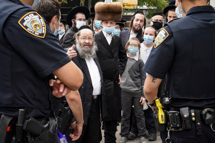 Members of the Orthodox Jewish community speak with NYPD officers on a street corner in the Borough Park neighborhood of Broo