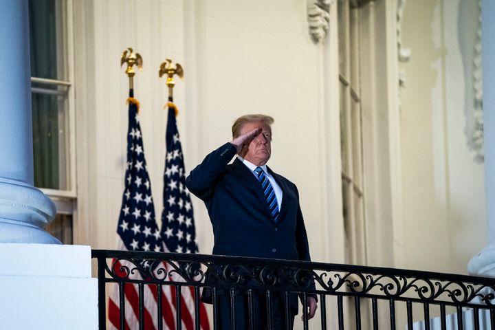 Donald Trump salutes to Marine One from the Truman Balcony as he returns home after receiving treatment at Walter Reed National Military Medical Center.