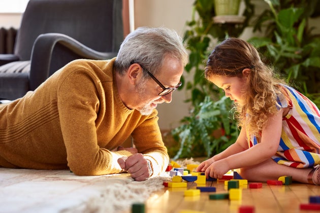 Mature man lying on floor playing with little girl, support, assistance, learning