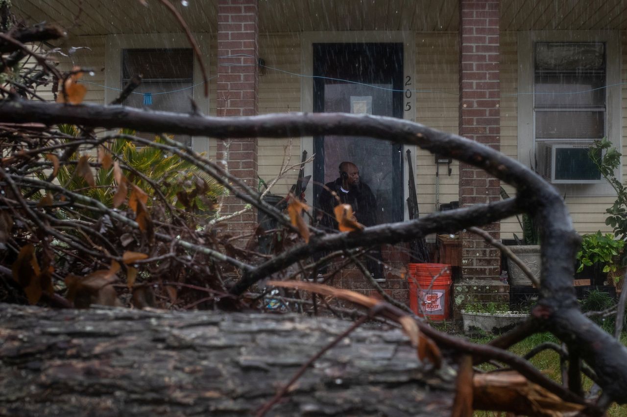 Michael Roberson, 46, is framed by debris from Hurricane Laura, as he watches the arrival of Hurricane Delta from his doorstep in Lake Charles, Louisiana.