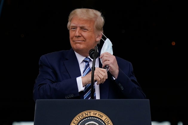 President Donald Trump removes his face mask to speak to a crowd of supporters, days after leaving hospital where he was being treated for Covid-19.