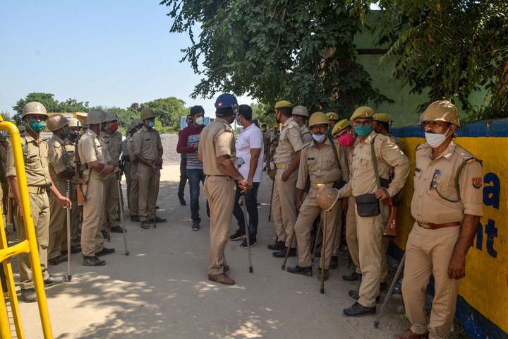 Police personnel stand guard blocking a road near the premises of the relatives of the 19-year-old woman allegedly gang-raped and killed by four men in Bool Garhi of Hathras district in Uttar Pradesh state on October 3, 2020. 