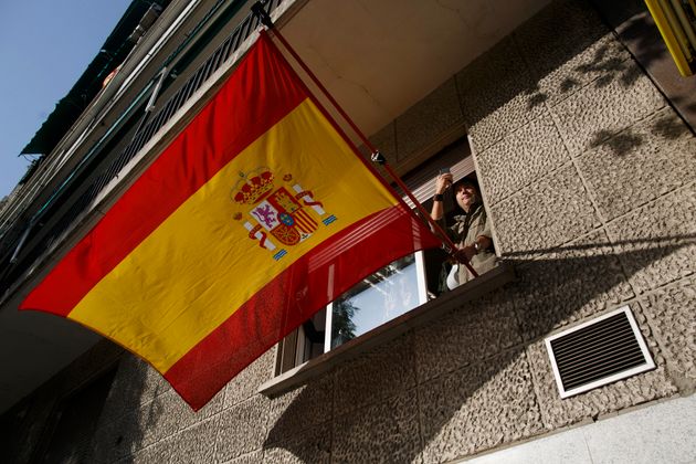 Un hombre enarbola una bandera de España, ante el desfile del 12 de Octubre de