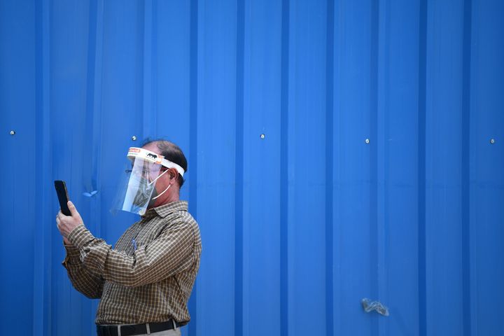 A man wearing a face shield over a facemask as a preventive measure against the Covid-19 coronavirus, uses his mobile phone along the roadside in New Delhi on September 16, 2020.