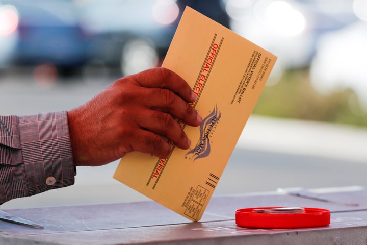 An election worker places a mail-in ballot into an election box at a drive-through drop-off location at the Registrar of Voters in San Diego in 2018.