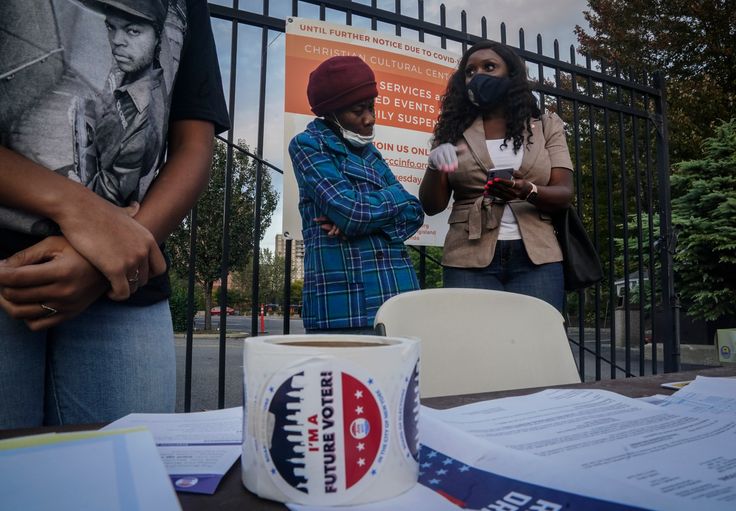 New York City Council member Farah Louis, right, who works as a volunteer with Christian Cultural Center's Social Justice Initiative's voter registration drive, tries to convince a woman to register at a table outside the the church, Thursday, Oct. 1, 2020, in the Brooklyn borough of New York. "