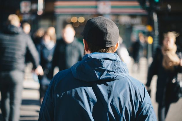 Rear view of man wearing blue jacket on city street during