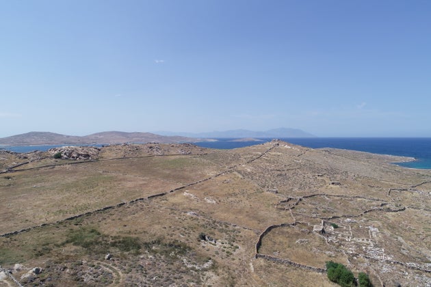 Η ελληνιστική νεκρόπολη της Δήλου στην Ρήνεια, ο πυραμιδοειδής  λόφος Χωμασοβούνι όπου πιθανολογείται η θέση του Αρεμισίου εν νήσω των δηλιακών επιγραφών, και αριστερά αρχαία αγροικία δίπλα σε νεώτερη, με αγροτικές εκτάσεις σε διαχρονική χρήση. Στο βάθος, το βόρειο τμήμα της Ρήνειας (οι Επάνω Δήλες) και στον ορίζοντα η Τήνας.
