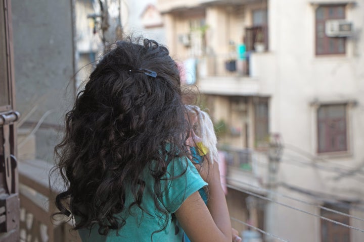 Girl child at her house balcony with her doll during lockdown period due to covid-19 epidemic.