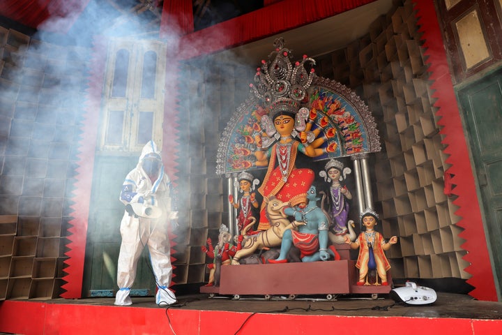 KOLKATA, WEST BENGAL, INDIA - 2020/10/13: A member of the Durga Puja committee dressed in a protective suit sprays disinfectants to sanitise a Pandal in front of an idol of Goddess Durga as a preventive measure against the spread of Coronavirus (COVID-19). (Photo by Jit Chattopadhyay/SOPA Images/LightRocket via Getty Images)