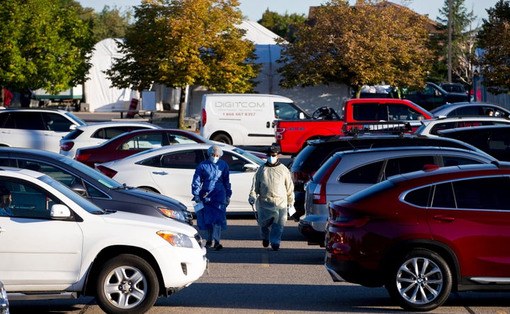 Two employees collect information from the people waiting in their cars at the Etobicoke General Hospital Drive-Thru coronavirus disease (COVID-19) testing facility in Etobicoke, Ont. on Sept. 18, 2020. 