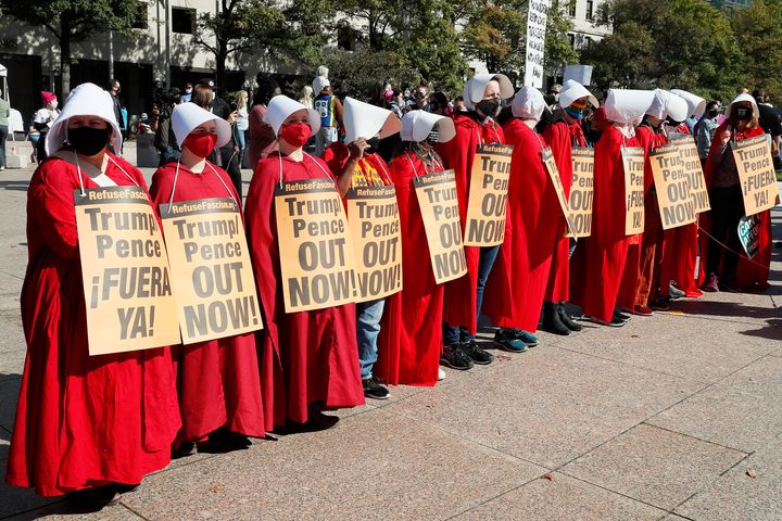 Women dressed as handmaidens protest against Donald Trump's presidency on Saturday.