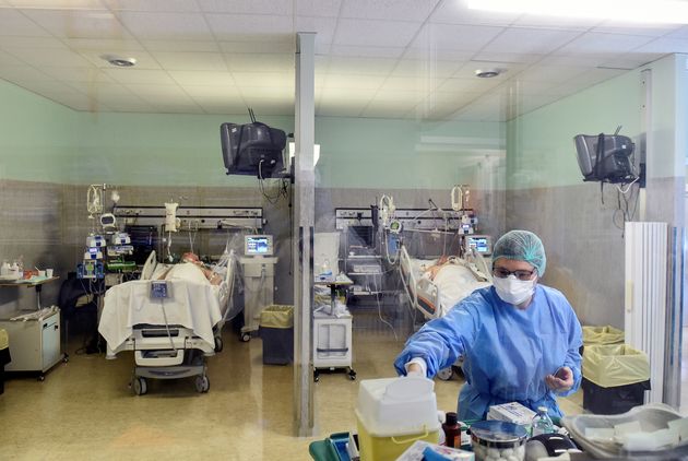 A medical worker wearing a protective mask and suit treats patients suffering from coronavirus disease ...