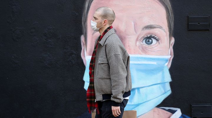 A person wearing a face mask walks past a mural of a nurse in Manchester, as the city is waiting to find out if the region will be placed into the Very High category with tier 3 lockdown restrictions to curb the spread of coronavirus.