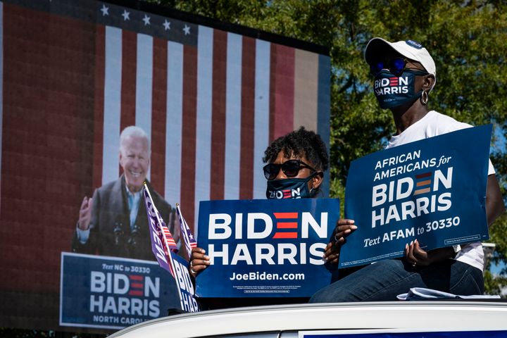 Supporters listen while sitting atop their car as Democratic presidential nominee Joe Biden speaks during a drive-in campaign rally at Riverside High School on October 18, 2020 in Durham, North Carolina.