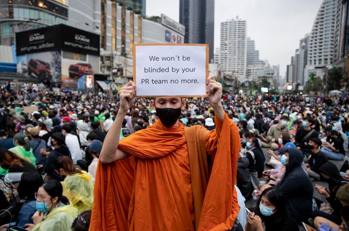 A Buddhist monk, supporter of pro-democracy movement, displays a placard during a protest rally at an intersection in Bangkok