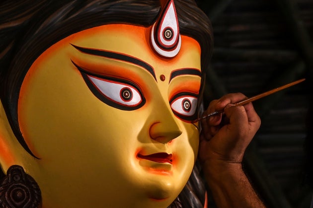 An artisan gives finishing touches on an idol of the ten-armed Hindu Goddess Durga at a makeshift place...
