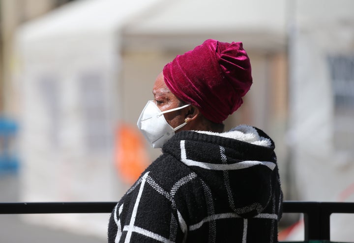 A woman wearing a face mask waits in a queue to access a walk-in pop-up covid19 drive-through testing centre in, Hackney, east London