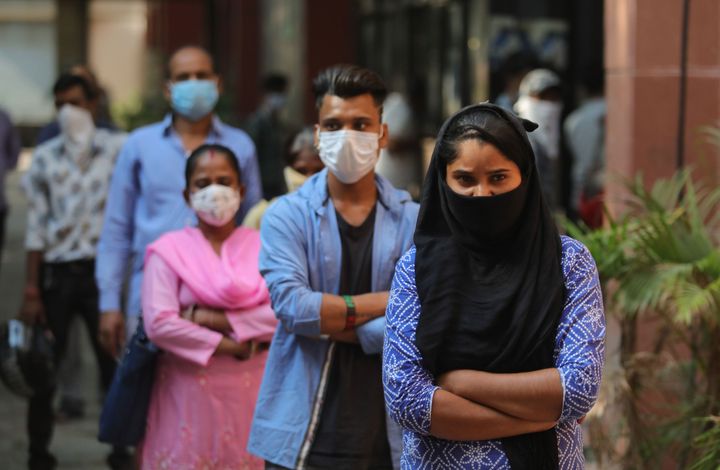 People wearing face mask wait in a queue for the Covid-19 Rapid Antigen test. 