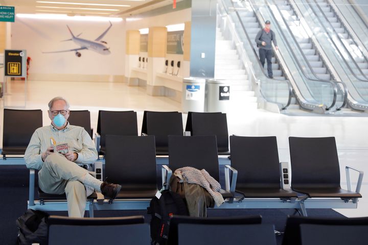 A traveler wears a mask while reading in John F. Kennedy International Airport in New York City. The CDC has advised that people on public conveyances — including trains, planes and buses — wear masks for the entire duration of their trip. 