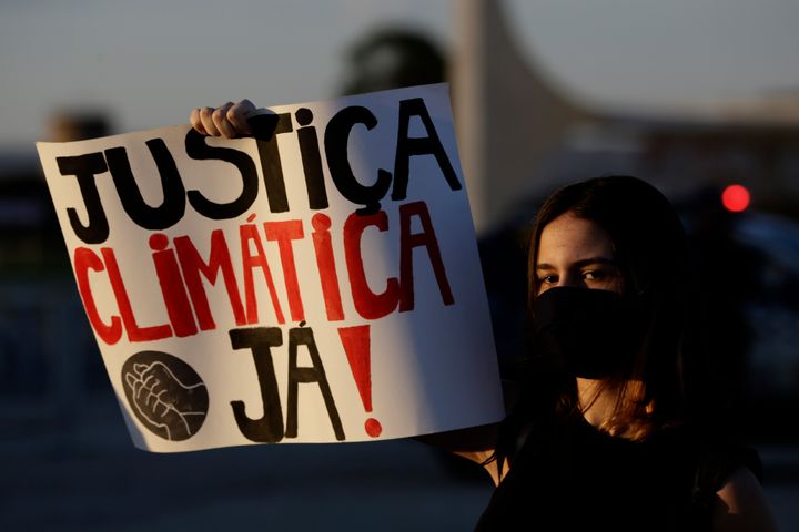 A woman holds a sign reading "Climate Justice Now!" during a protest against Bolsonaro's environmental policies in the Brazilian capital of Brasilia. Bolsonaro has faced domestic and international pressure to alter his approach to the environment.