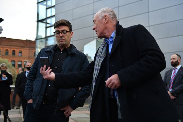Greater Manchester mayor Andy Burnham (left) with leader of Manchester City Council Sir Richard showing him when the measures will come into force after speaking to the media outside Bridgewater Hall, Manchester.
