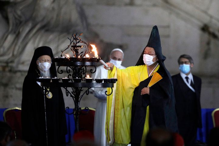 Buddhist monk Shoten Minegishi lights a candle for peace as Bartolomew I, Patriarch of Constantinopole, Pope Francis and Haim Korsia, Chief Rabbi of France, look on, during an inter-religious ceremony for peace in the square outside Rome's City Hall on Oct. 20, 2020.