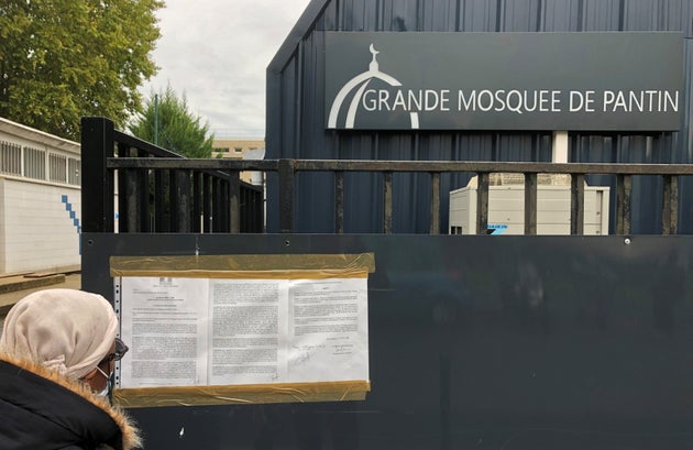 A woman reads a prefectoral decree installed on the entrance gates of the Grand Mosque of Pantin, near...