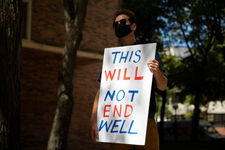 A faculty member holds a sign as students and faculty protest in-person classes for the fall semester at the University of Mi
