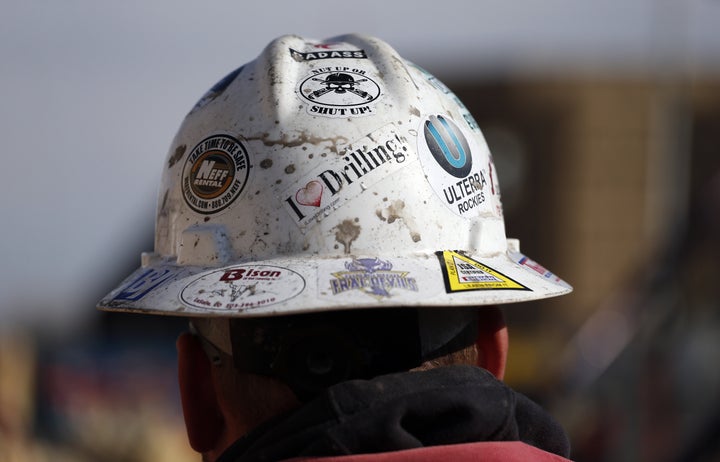 A worker wears a protective helmet decorated with stickers during a hydraulic fracturing operation at an oil well near Mead, Colorado.