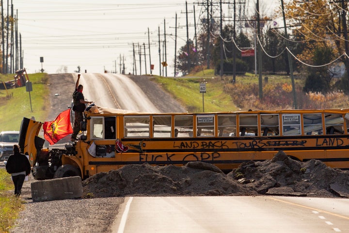 A land defender stands on a bus blocking Argyle Street South in Caledonia, Ont., after a judge granted a permanent injunction against a land reclamation camp known as 1492 Land Back Lane on Friday,