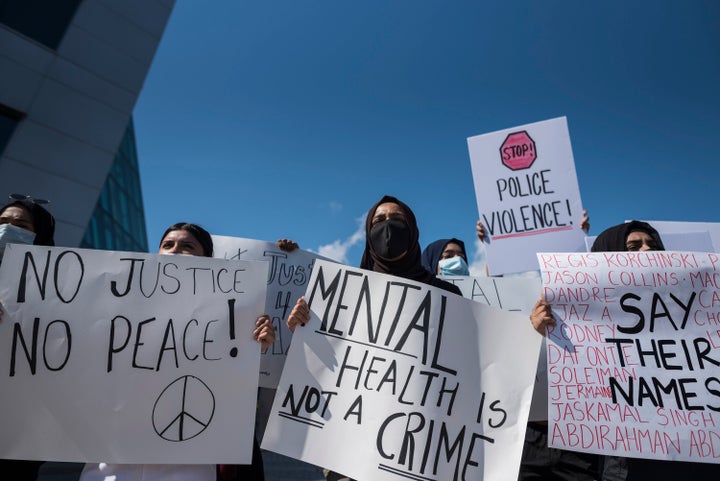 People hold signs outside Peel Regional Police Headquarters during a justice rally for Ejaz Choudry.