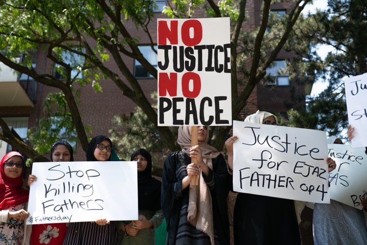 Protestors hold signs in front of the apartment building where Ejaz Choudry, a 62-year-old man who family members said was experiencing a schizophrenic episode, was shot by Peel Police and died at the scene the previous night, in Mississauga, Ont. on June 21, 2020.