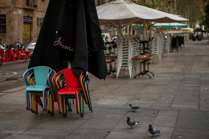Chairs and tables are piled up on a bar terrace closed due to sharpest resurgences of the new coronavirus in Barcelona, Spain, Monday, Oct. 19, 2020. 