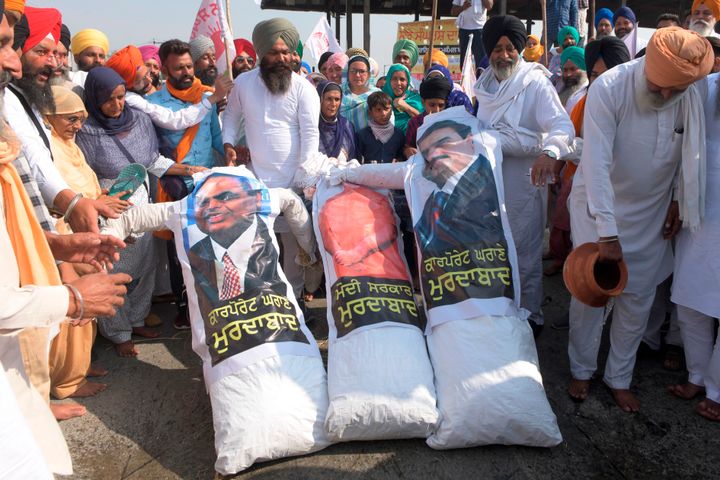 Farmers shout slogans before burning effigies of Prime Minister Narendra Modi, Chairman of Reliance Industries Ltd company, Mukesh Ambani and Chairman and founder of the Adani Group Gautam Adani, to protest against corporate businesses following the recent passing of agriculture bills in the Parliament, on the outskirts of Amritsar on October 18, 2020. 