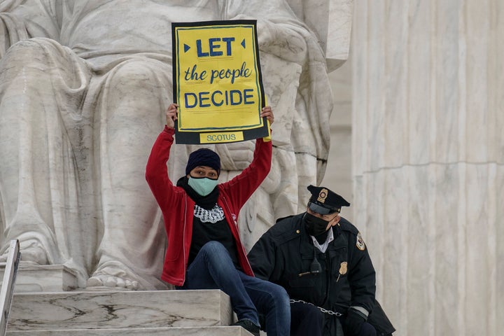 A protester opposed to the Senate's race to confirm Amy Coney Barrett is removed by police after chaining themselves to a rai